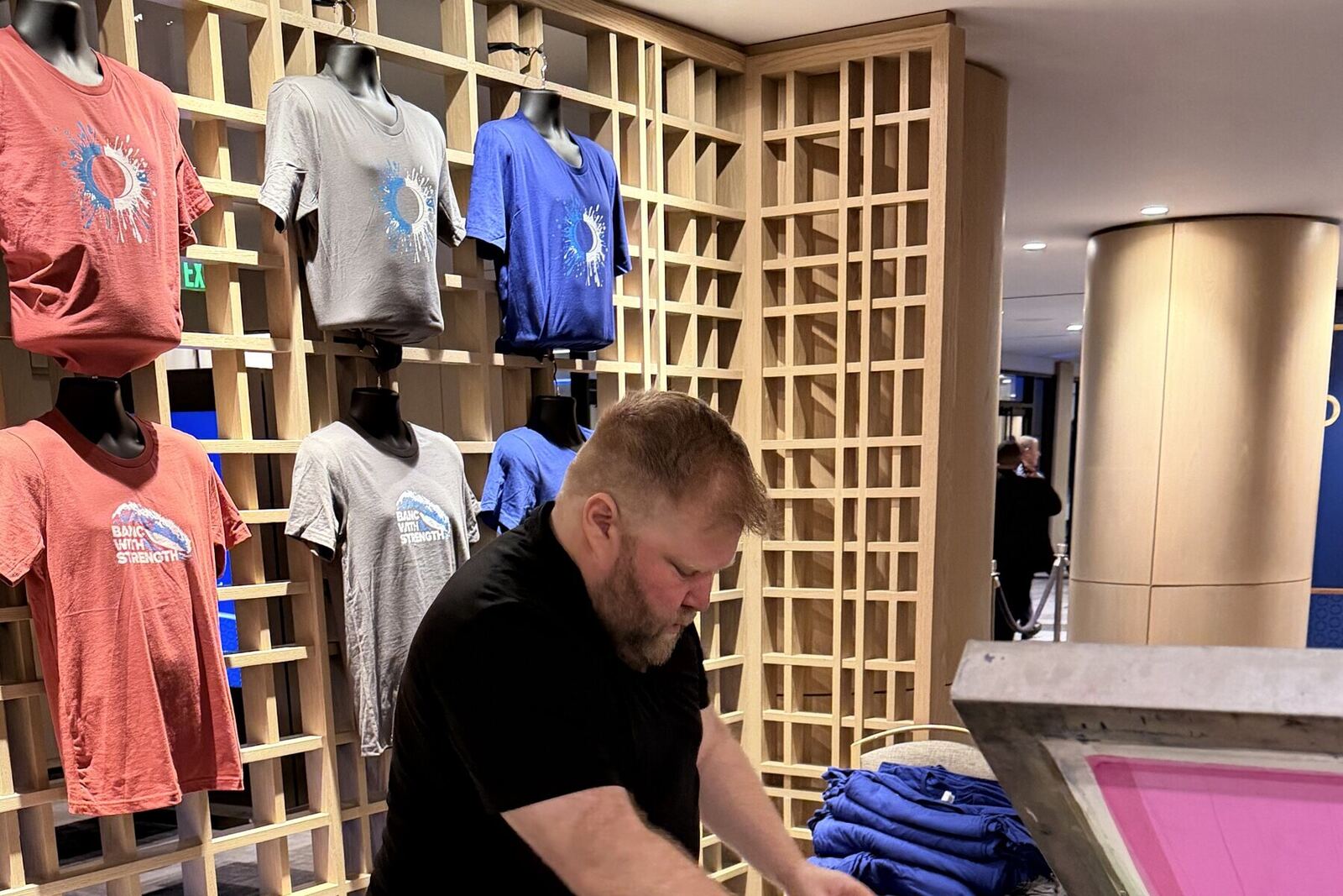 Rack of freshly printed shirts displayed at a trade show booth