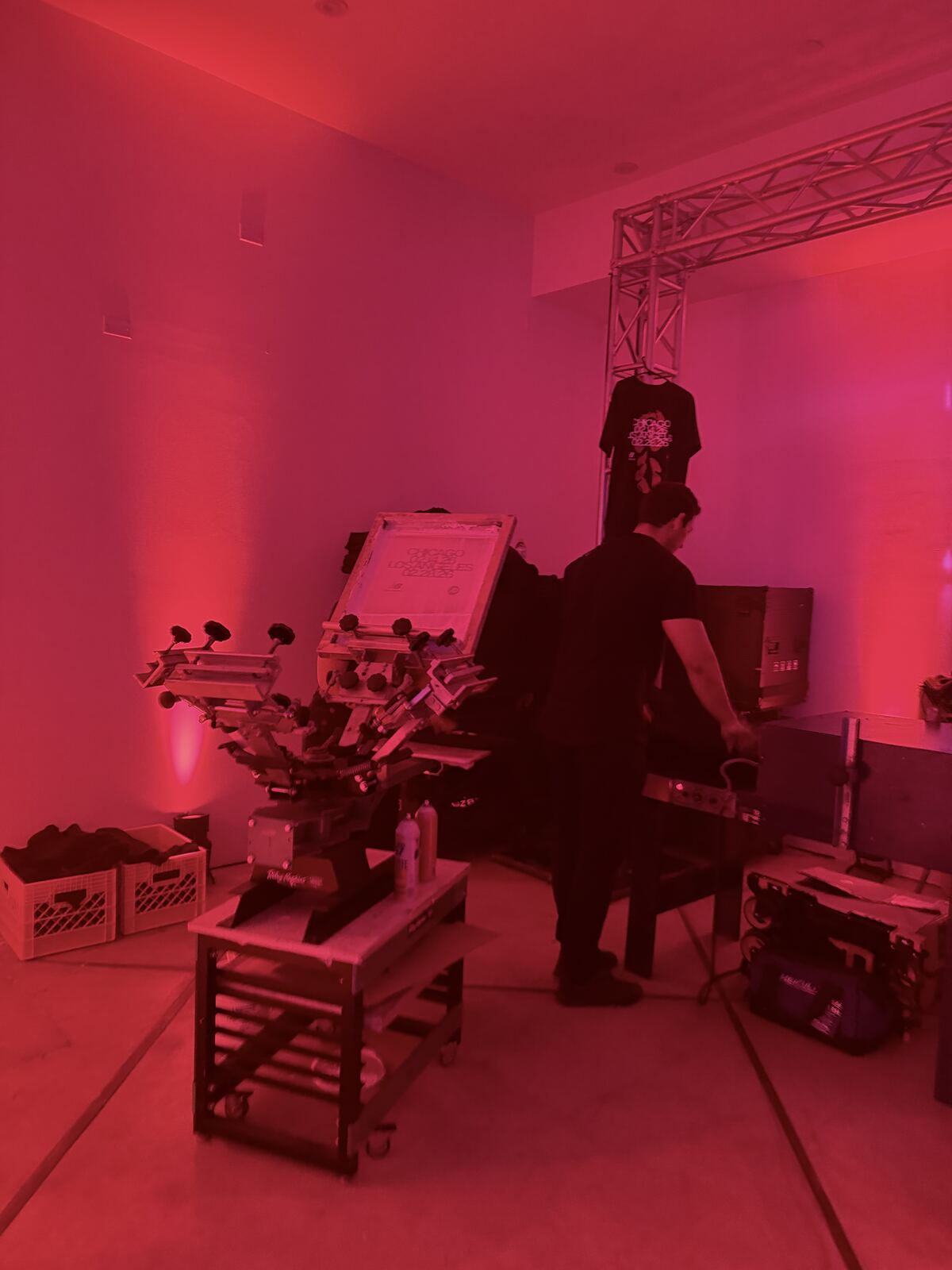 Operator demonstrating screen printing equipment at a professional event booth with vibrant magenta lighting